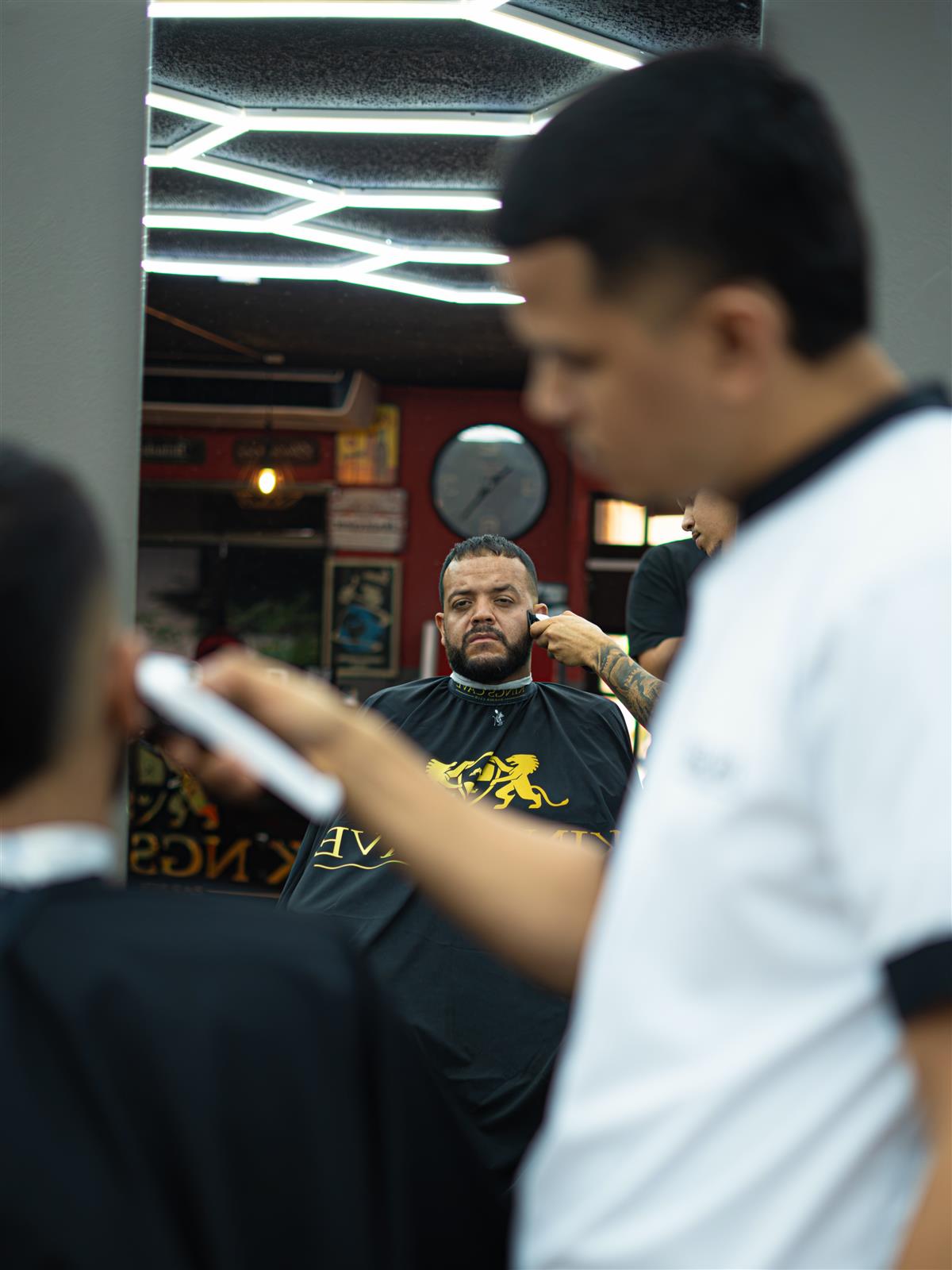 Barbero de Kings Cave cortando el cabello frente al espejo