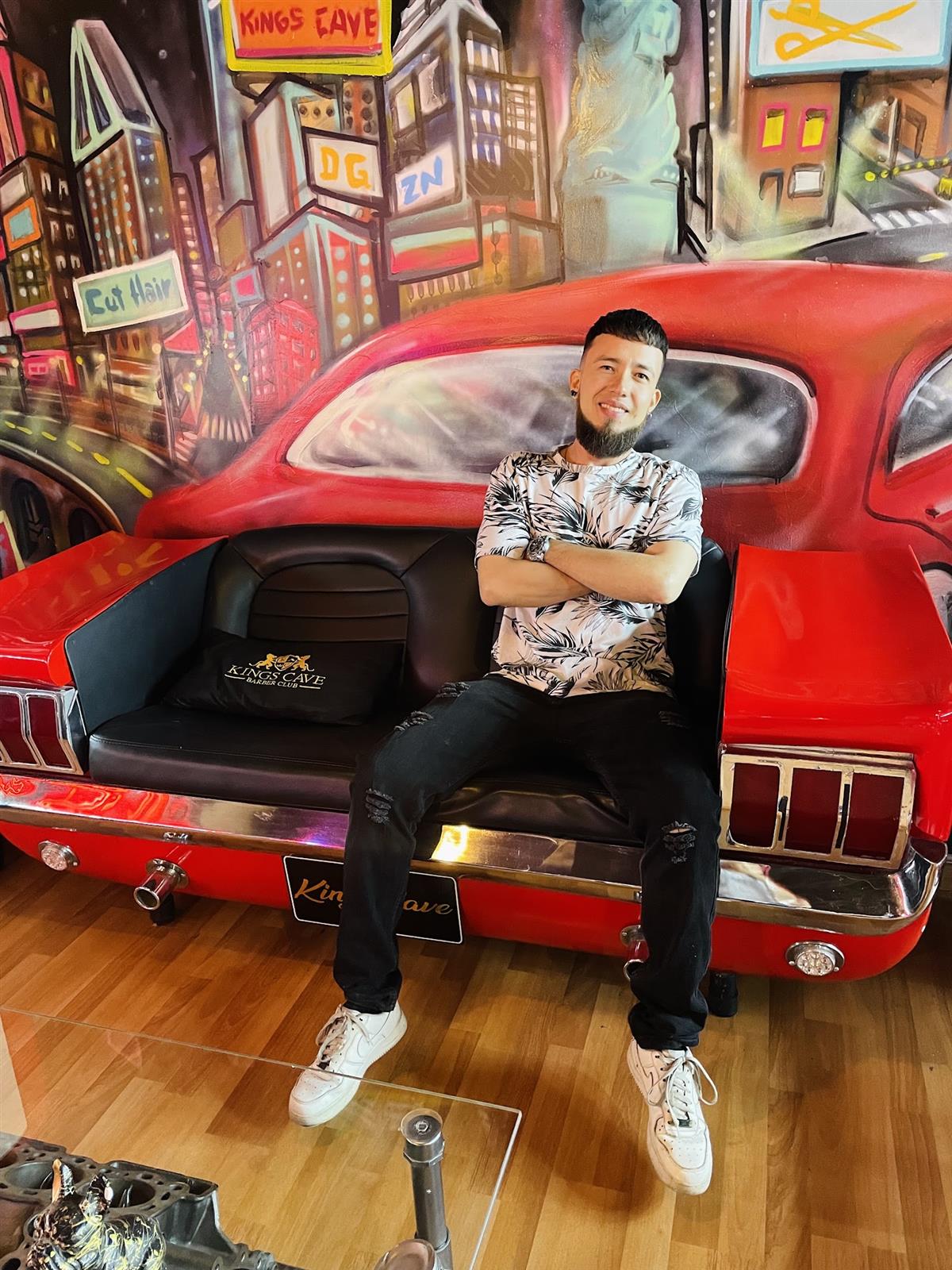Sofá hecho con la parte trasera de un Mustang rojo frente a un mural de ciudad
