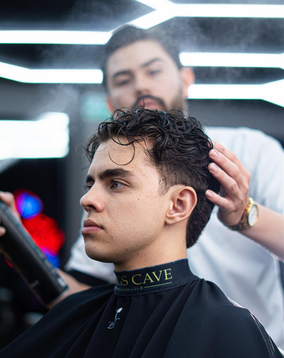 Cliente con rizos y fade, capa negra de Kings Cave